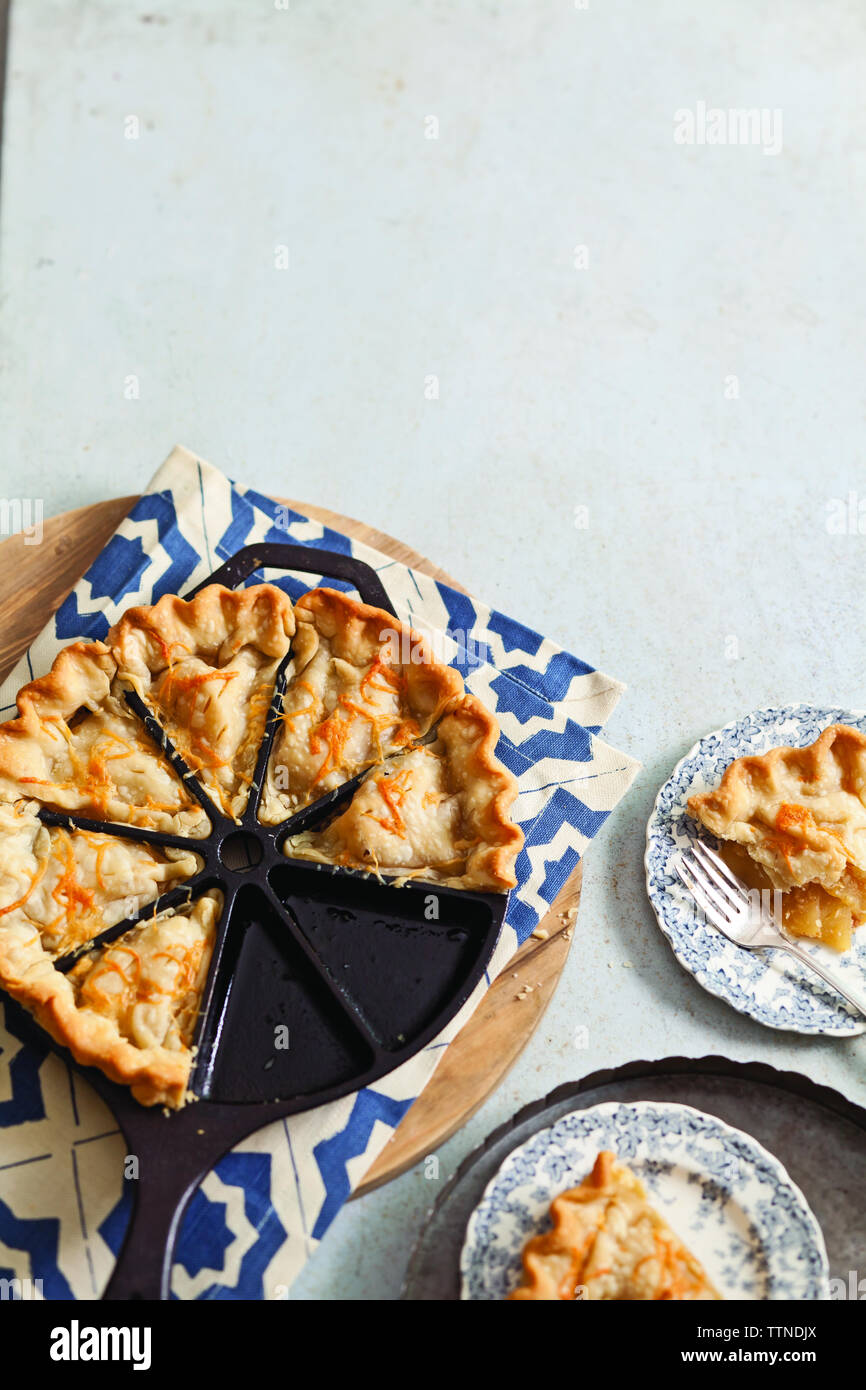 Vue en grand angle de la tarte aux pommes dans un moule à pâtisserie avec des assiettes sur la table Banque D'Images
