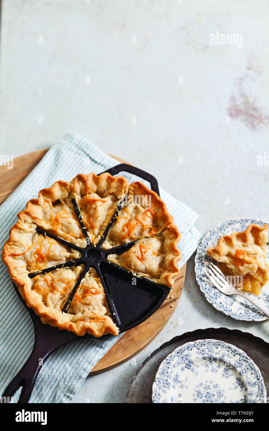 Vue en grand angle de la tarte aux pommes dans un moule à pâtisserie avec des assiettes sur la table à la maison Banque D'Images