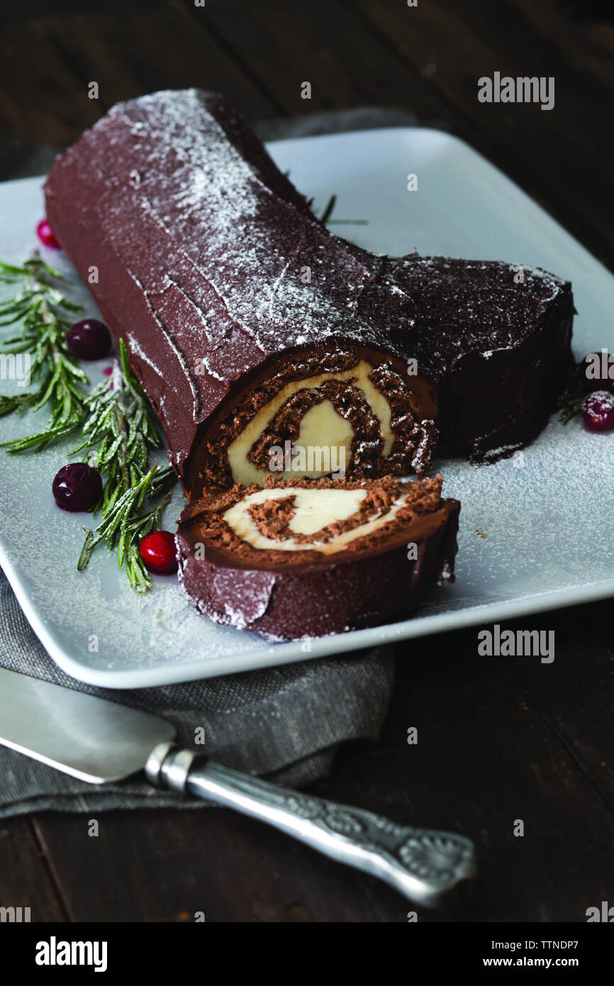 Vue en grand angle de la bûche de yules servie avec du romarin dans une assiette sur la table à la maison pendant Noël Banque D'Images