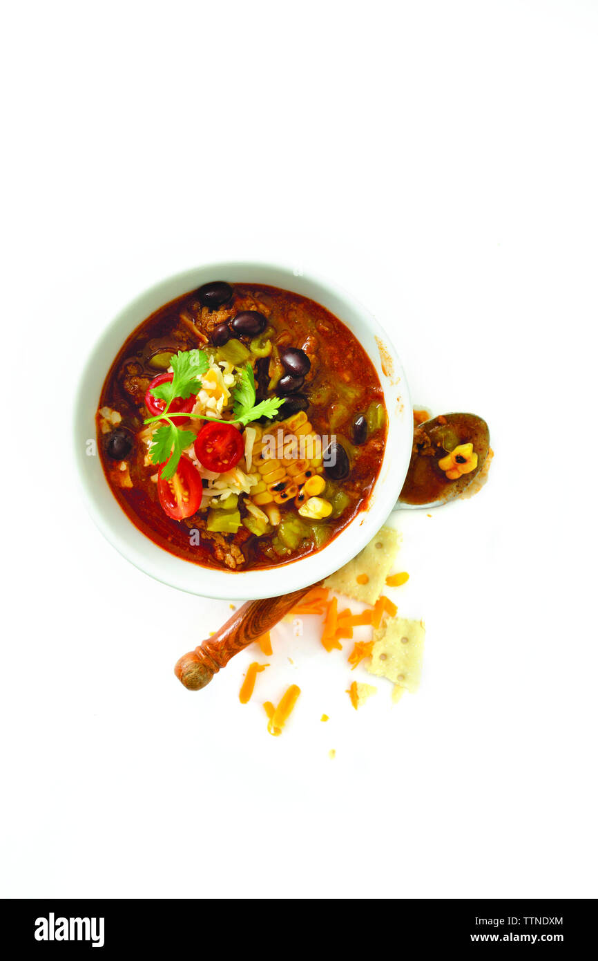Vue en grand angle du curry servi dans un bol avec une cuillère sur fond blanc Banque D'Images