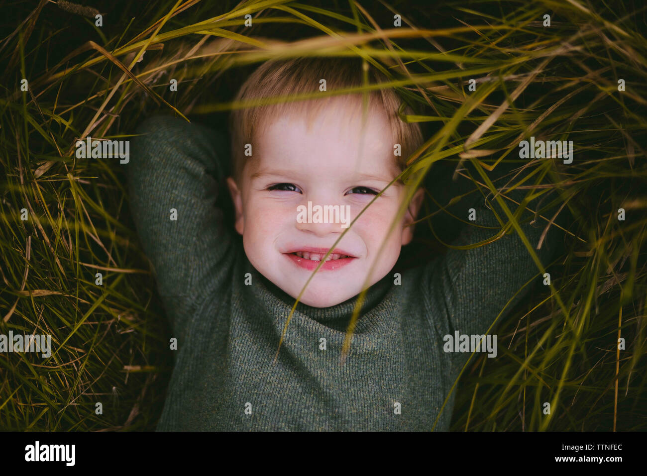 Close-up of cute carefree boy lying on grassy field Banque D'Images