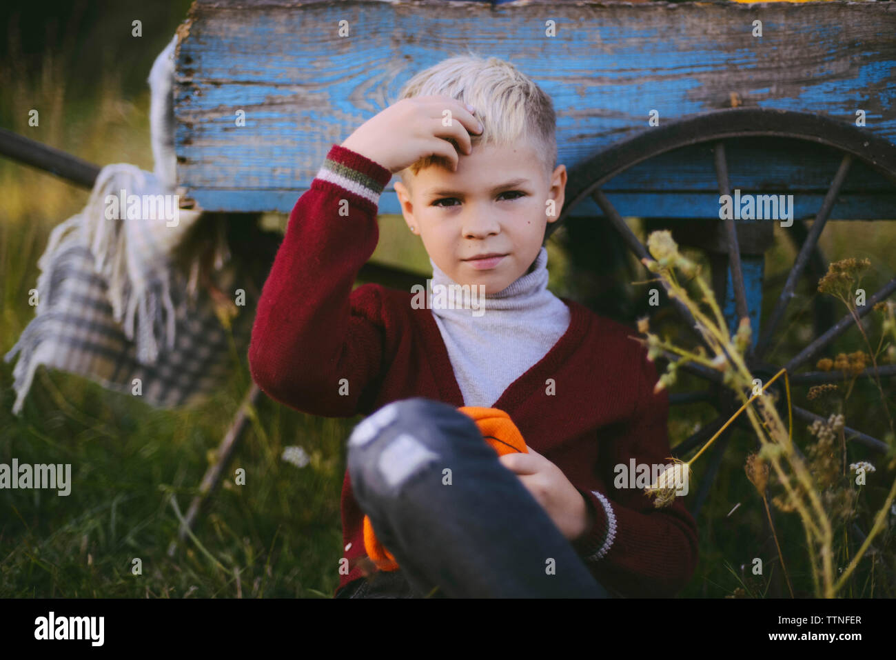 Portrait of boy touching hair while sitting contre panier sur terrain Banque D'Images