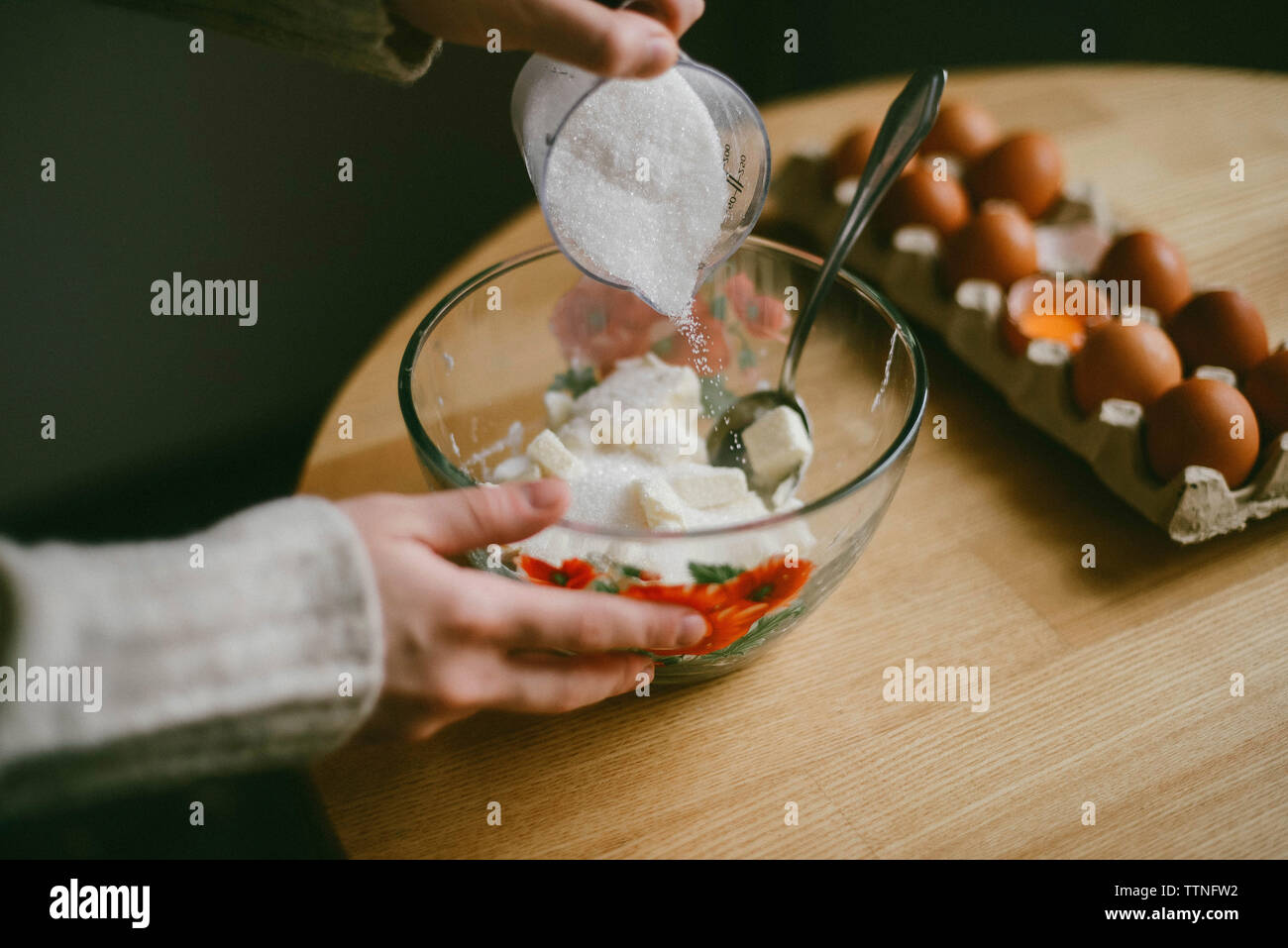 Les mains coupées de femme faisant la pâte dans un bol sur la table en bois à la maison Banque D'Images