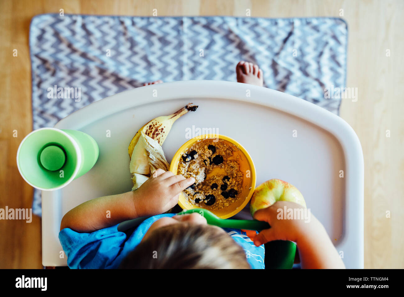 Vue de dessus de garçon de manger des aliments dans une chaise haute Banque D'Images