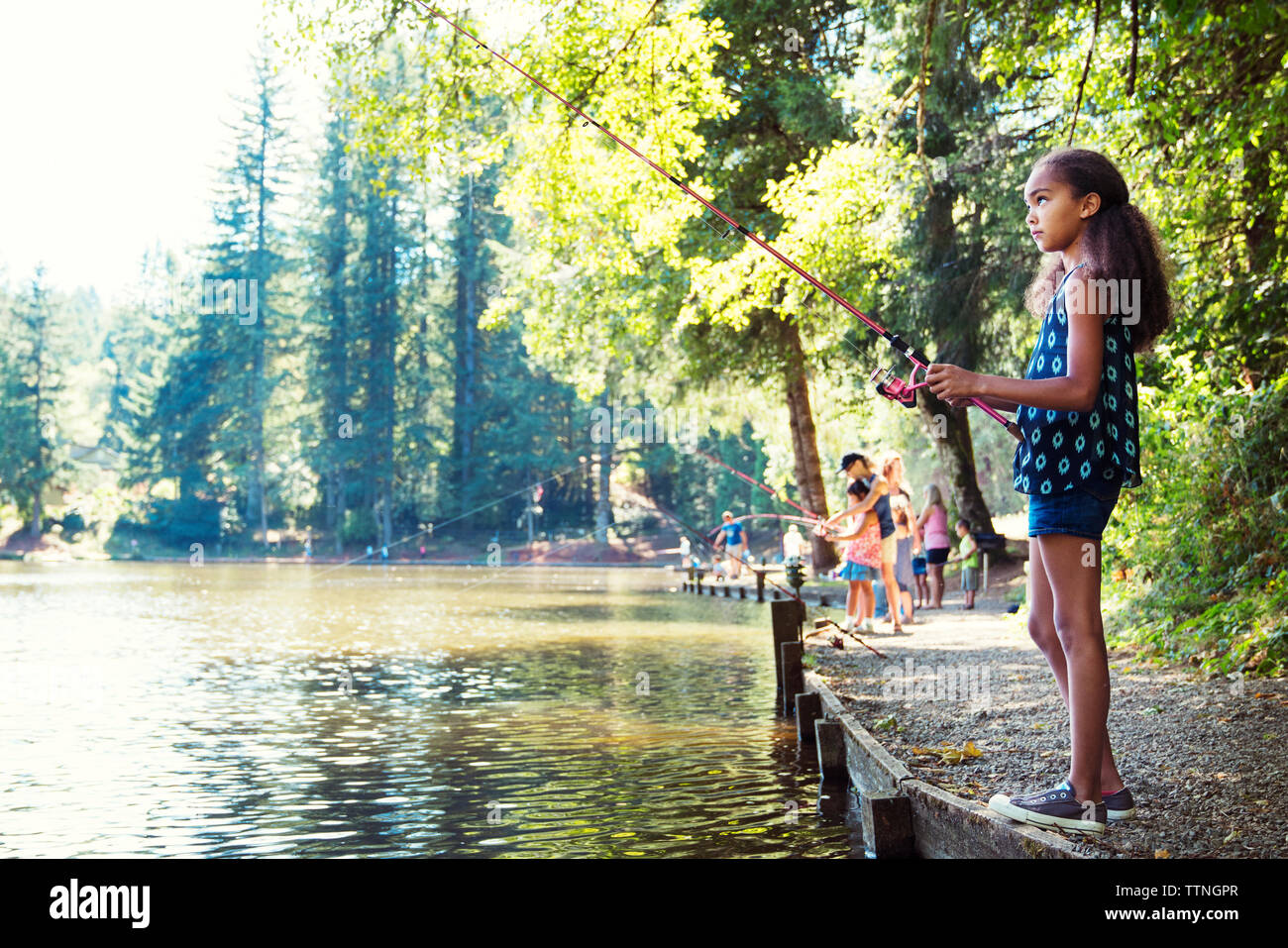 Vue latérale du girl la pêche dans le lac aux beaux jours Banque D'Images