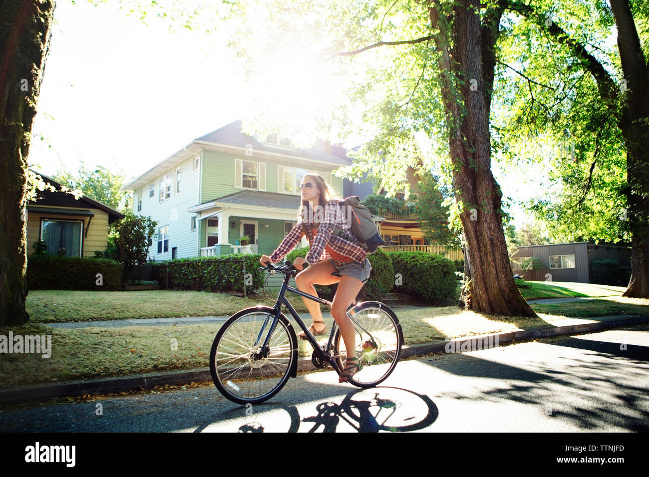 Toute la longueur de woman riding bicycle sur rue pendant l'été Banque D'Images