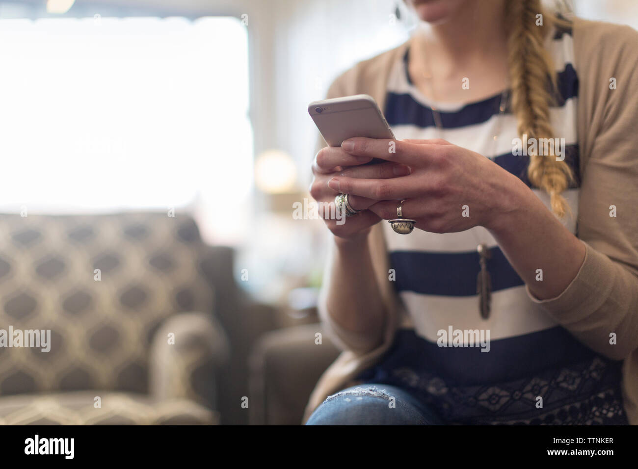 Portrait de la clientèle féminine à l'aide de smart phone while sitting in furniture store Banque D'Images
