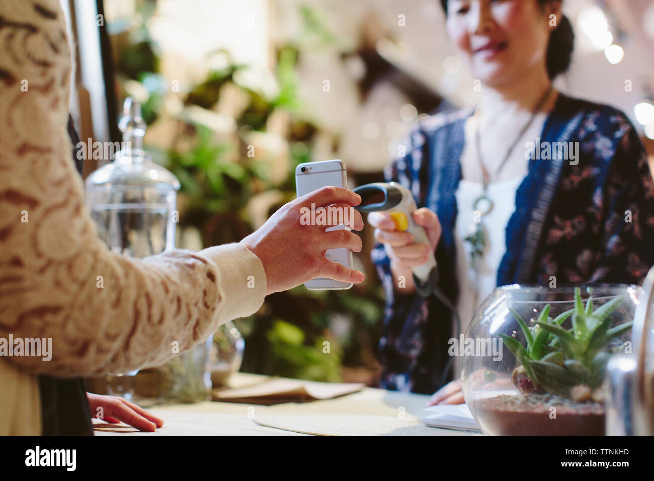 Portrait customer holding mobile phone while scanning QR code propriétaire dans l'usine shop Banque D'Images