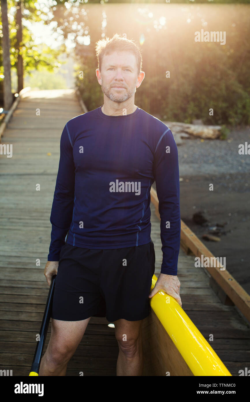 Portrait d'homme avec paddleboard debout sur boardwalk Banque D'Images