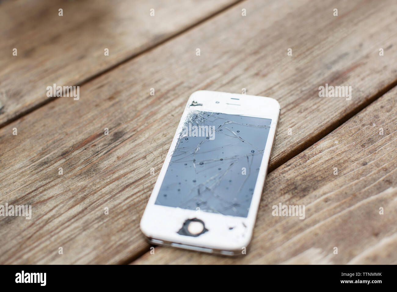 Close-up de téléphone intelligent avec écran fissuré sur table en bois Banque D'Images