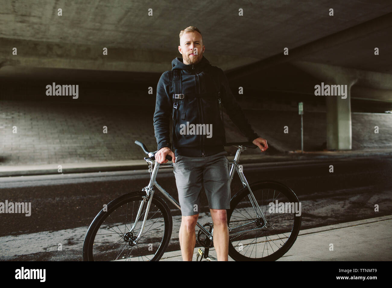 Portrait de l'homme confiant permanent de banlieue en vélo sur le pont Banque D'Images