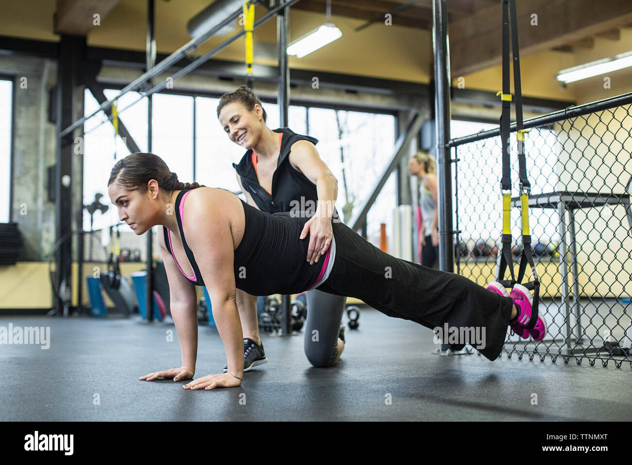 Aider l'instructeur femme en équilibre sur les jambes avec des bandes de résistance de fitness ay Banque D'Images