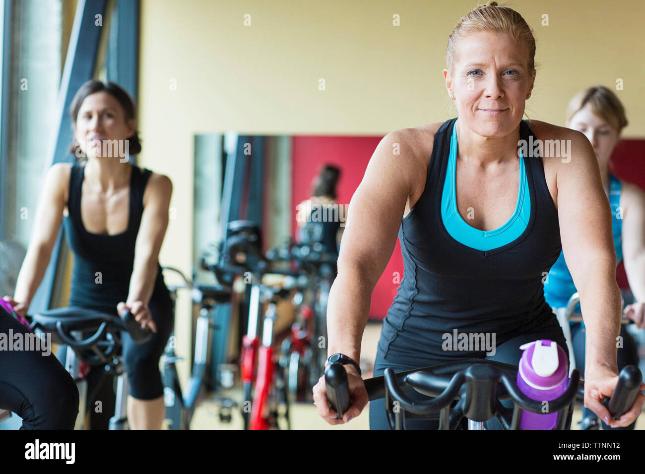 Les femmes exerçant sur les vélos d'exercice dans la salle de sport Banque D'Images
