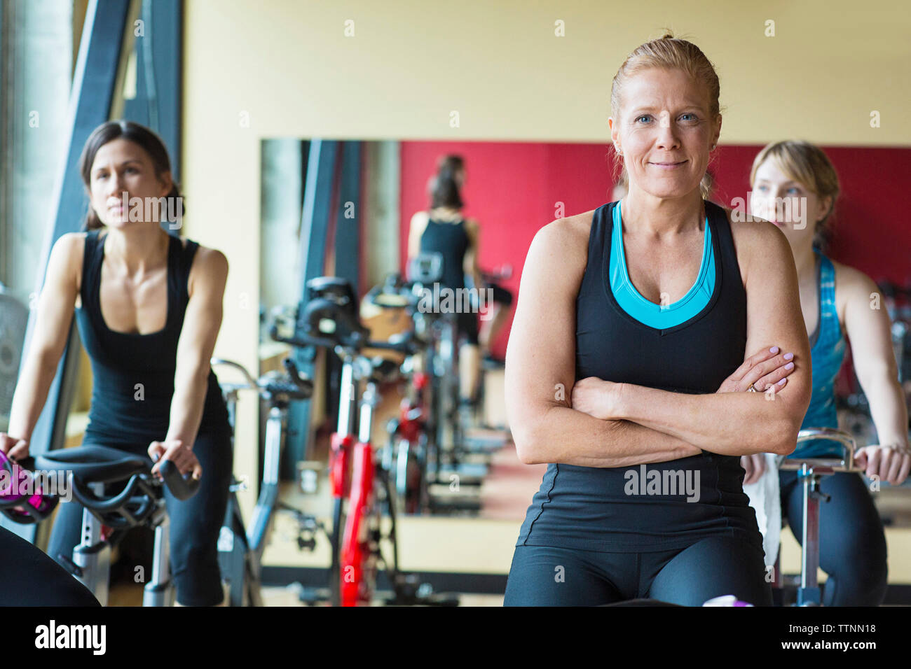 Portrait of woman on exercise bike avec des amis dans une salle de sport Banque D'Images