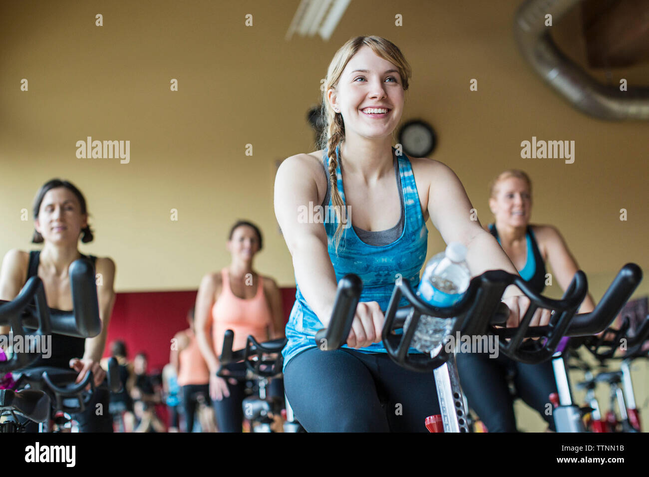 Smiling women vélo sur des vélos d'exercice à la salle de sport Banque D'Images