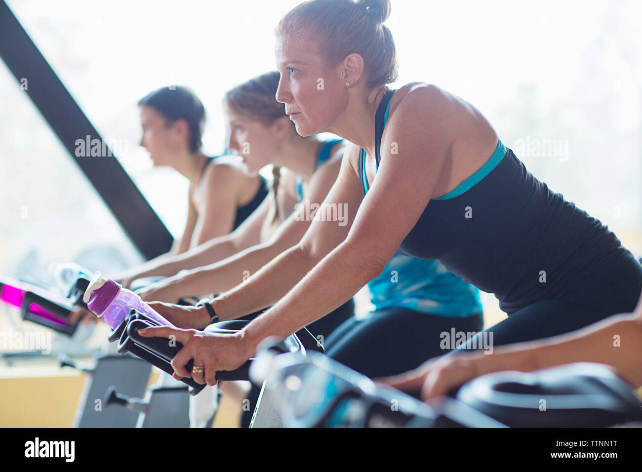 Les femmes à vélo sur des vélos d'exercice au club de santé Banque D'Images