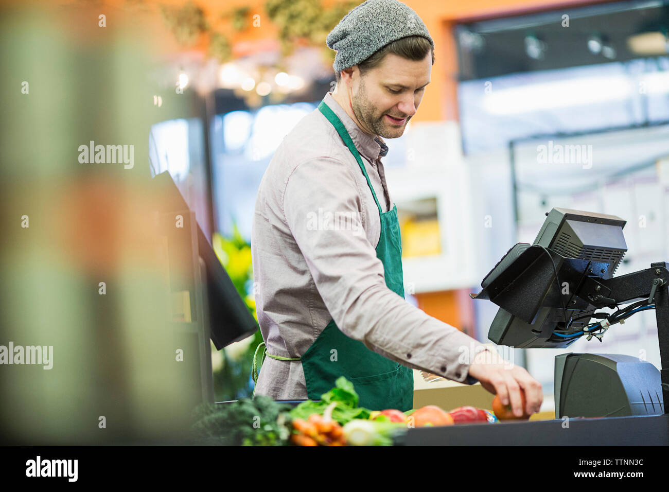 L'homme de travailler debout par comptoir de supermarché Banque D'Images