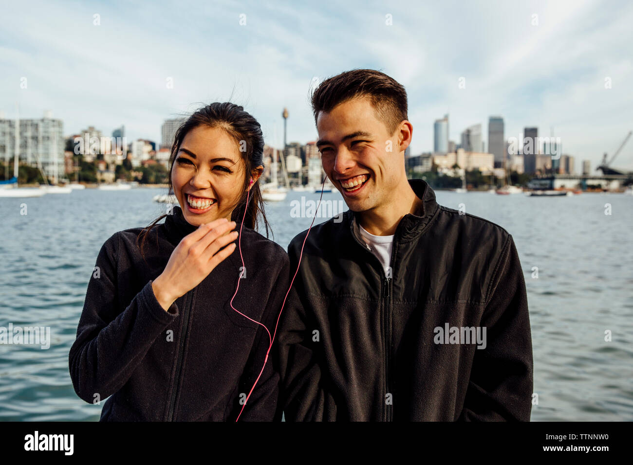 Jeune couple sympathique à l'écoute de la musique tout en exerçant contre cityscape Banque D'Images