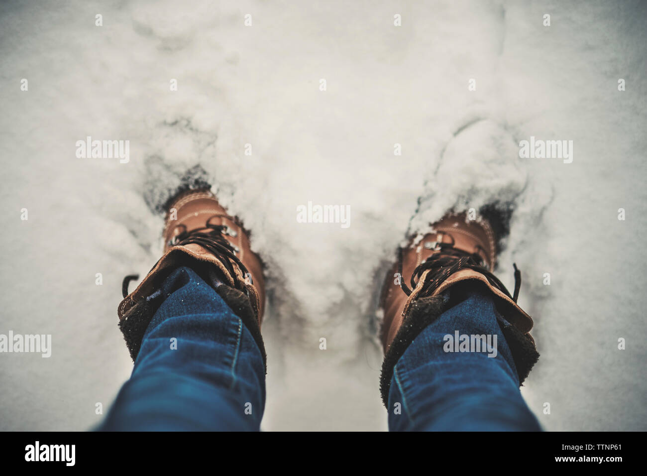 La section basse de l'homme debout sur le terrain couvert de neige Banque D'Images