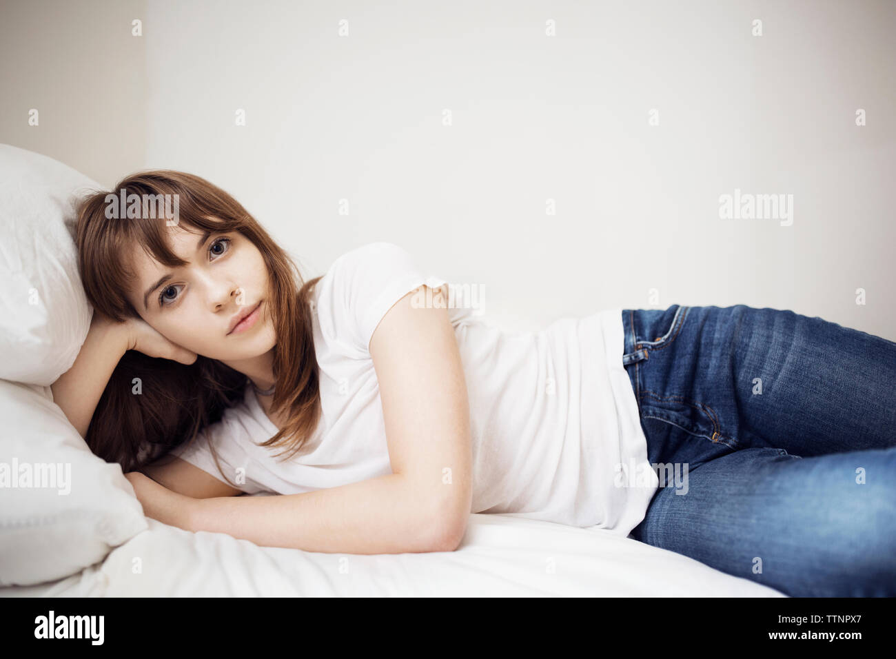 Portrait of young woman lying on bed at home Banque D'Images
