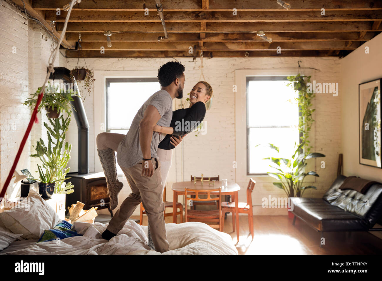 Cheerful multi-ethnic couple dancing on bed at home Banque D'Images