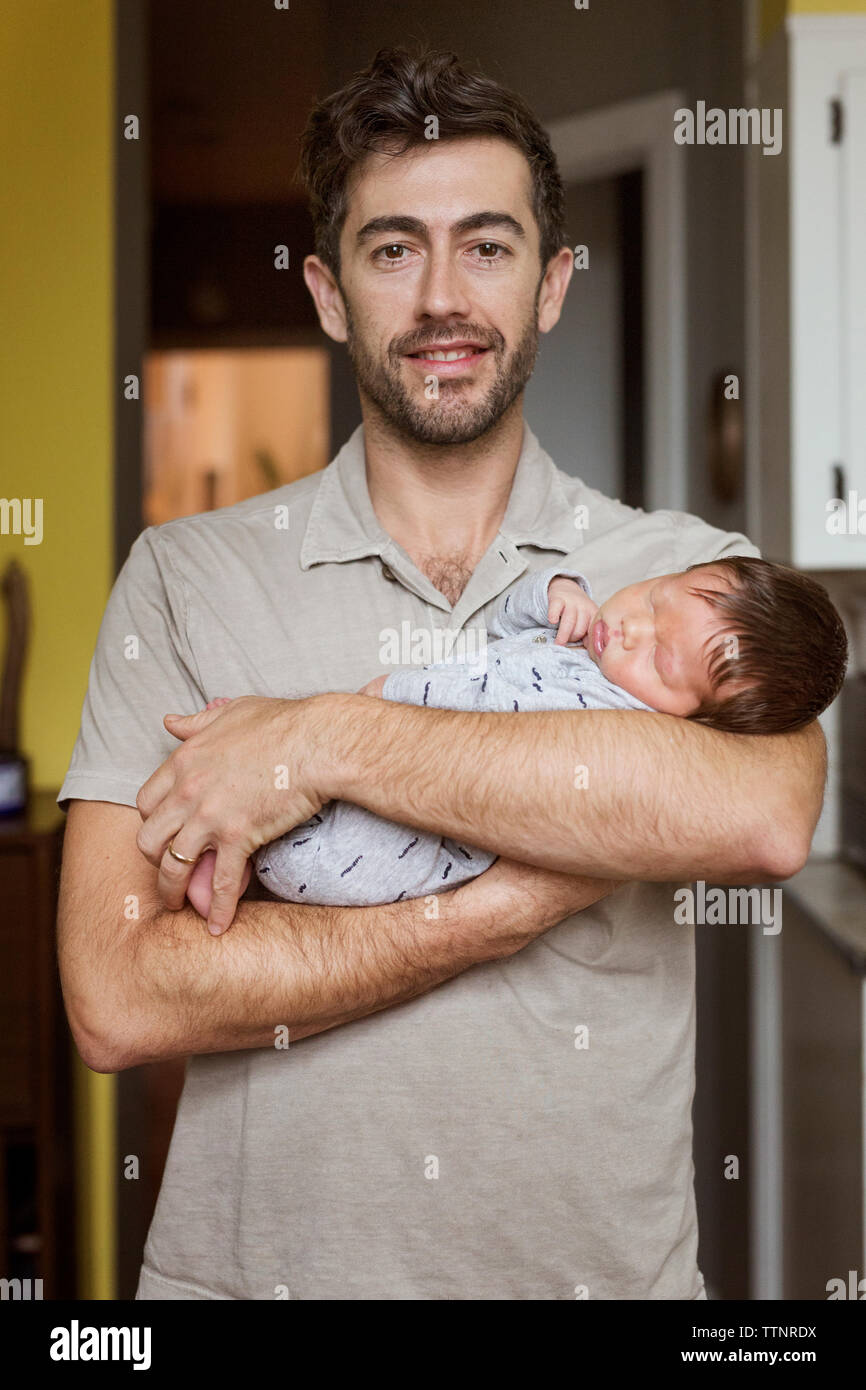 Portrait of happy father carrying baby boy at home Banque D'Images