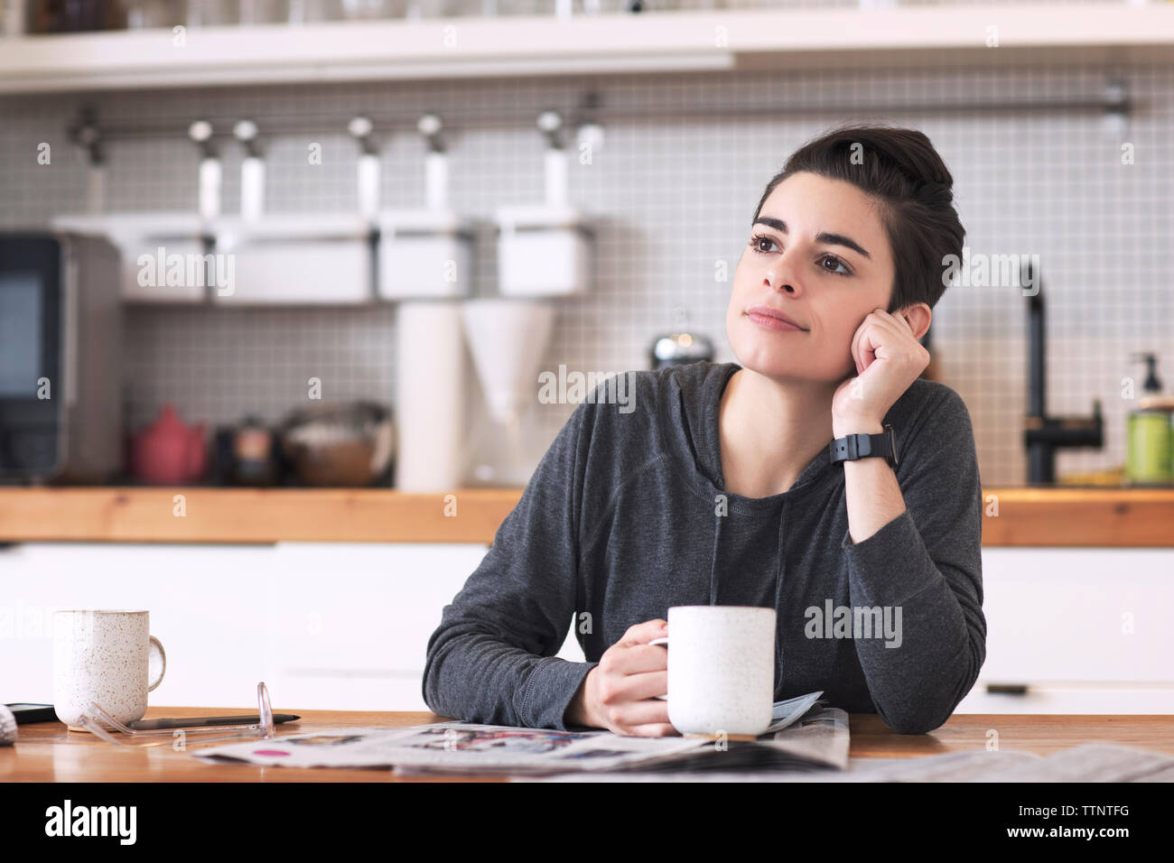 Femme avec des journaux et du café tasse à l'écart tout en étant assis à table à manger Banque D'Images Femme avec des journaux et du café tasse à l'écart tout en étant assis à table à manger Banque D'Images