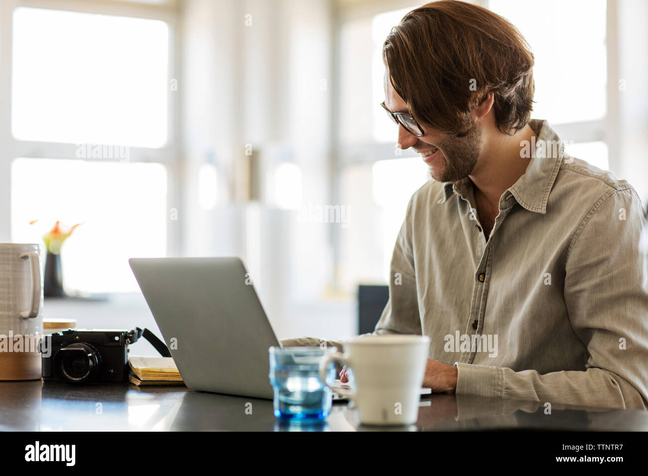 Smiling man using laptop computer sur l'île de cuisine à la maison Banque D'Images