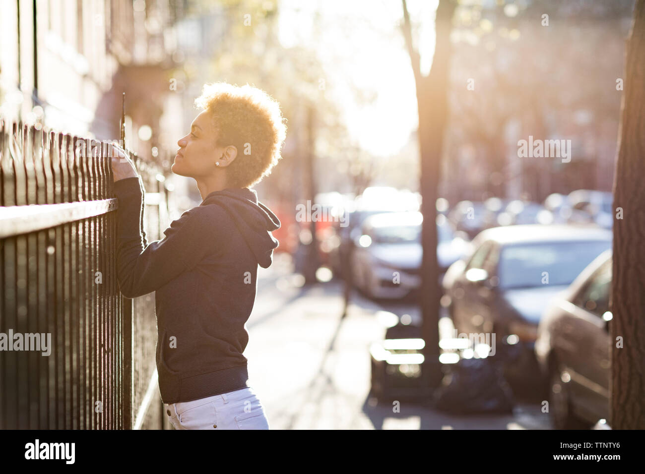 Jeune femme peeking sur rambarde en se tenant sur le trottoir Banque D'Images
