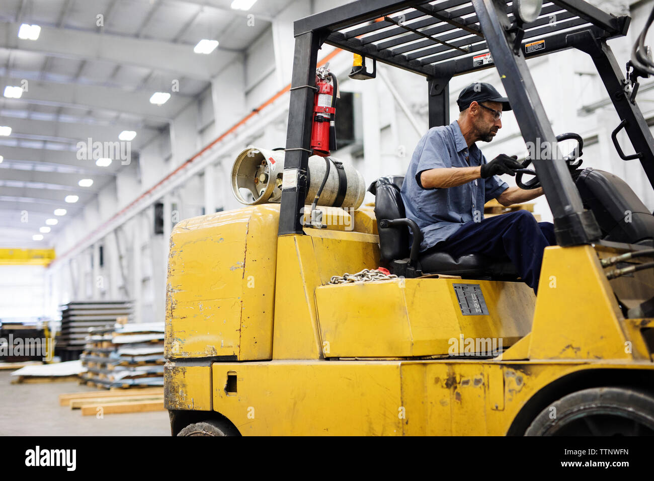 Travailleur homme driving forklift in warehouse Banque D'Images