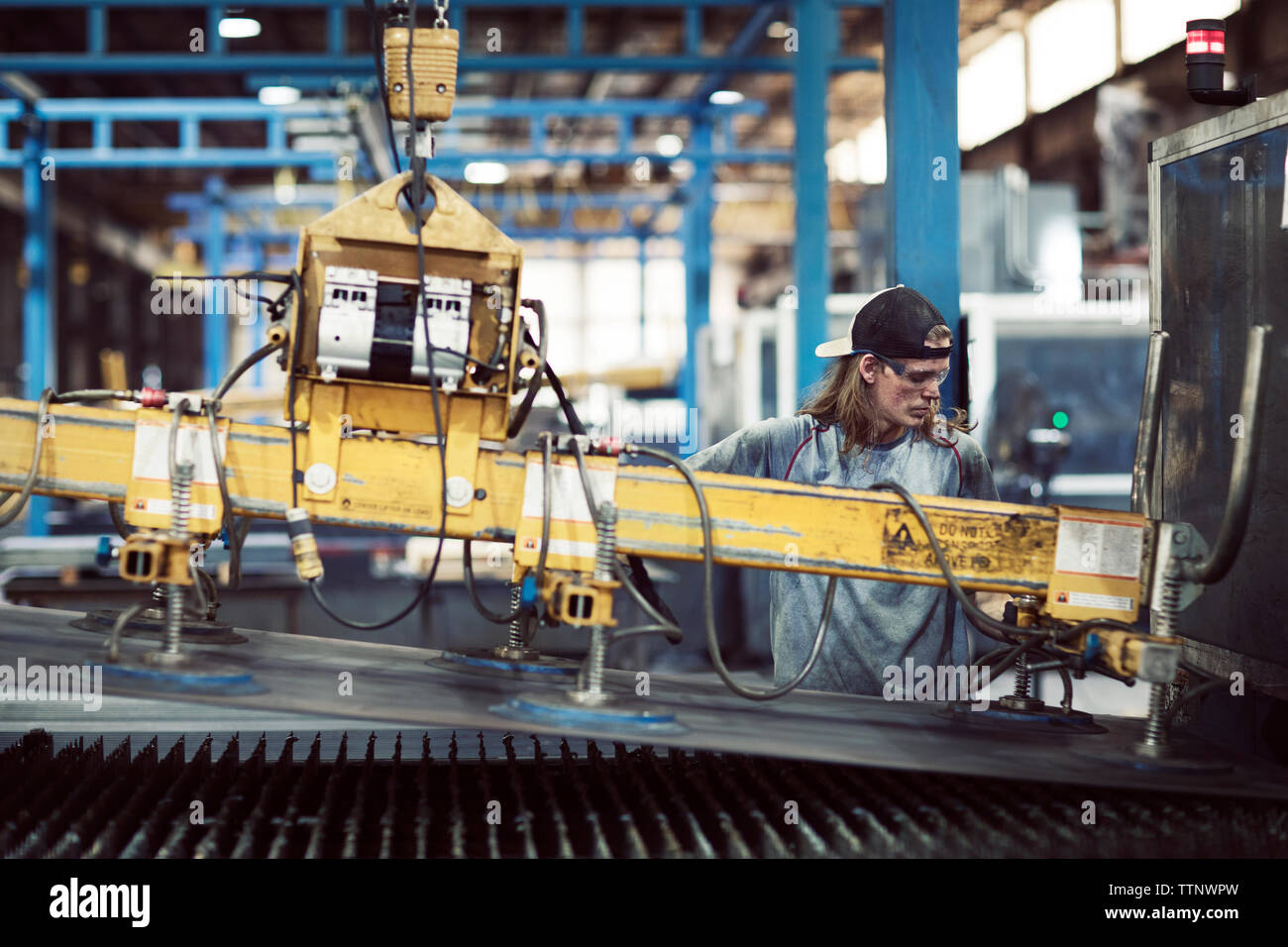 Travailleur de l'acier à l'aide de machines tout en travaillant en usine Banque D'Images