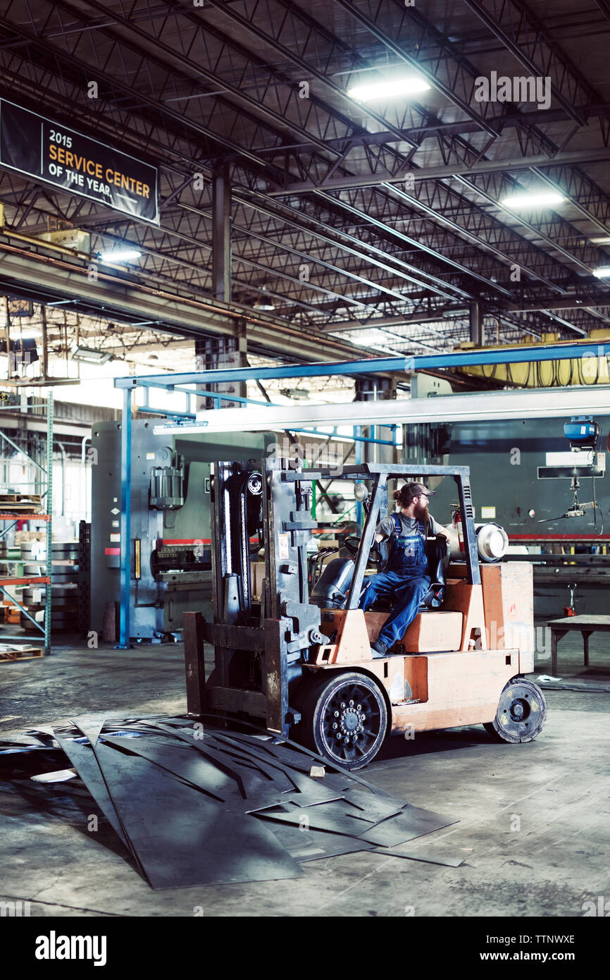 Travailleur homme roulant chariot par des tôles d'acier à l'industrie Banque D'Images