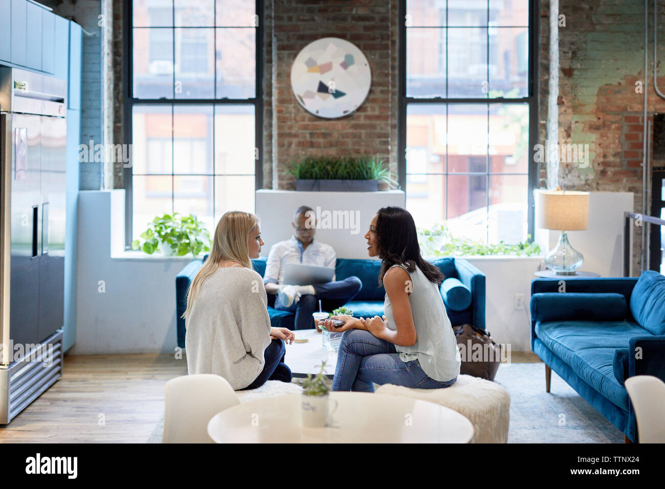femmes d'affaires communiquant tandis que collègue masculin travaillant sur ordinateur portable au bureau Banque D'Images