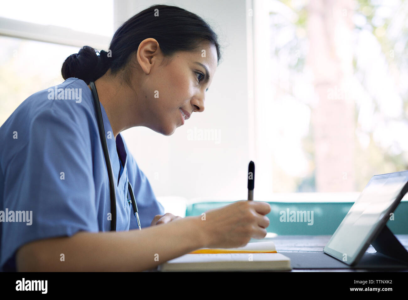 Vue latérale du doctor using tablet computer tout en travaillant dans une clinique médicale Banque D'Images