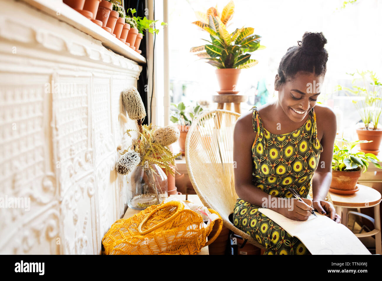 Femme écrit sur l'application notes tout en étant assis sur une chaise par store Banque D'Images