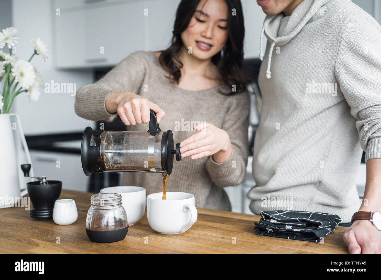 Femme avec petit ami pouring coffee dans cups à table Banque D'Images Femme avec petit ami pouring coffee dans cups à table Banque D'Images