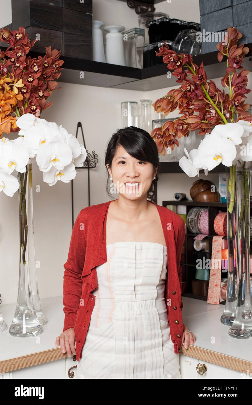 Portrait de femme propriétaire debout près des fleurs sur le cabinet à stocker Banque D'Images