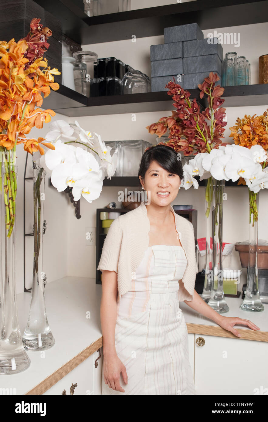 Portrait de femme propriétaire debout par des fleurs en magasin Banque D'Images