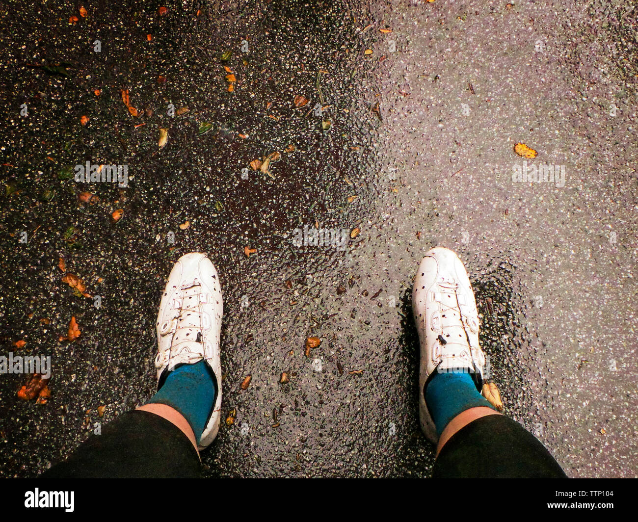 La section basse de l'homme debout sur la rue humide Banque D'Images