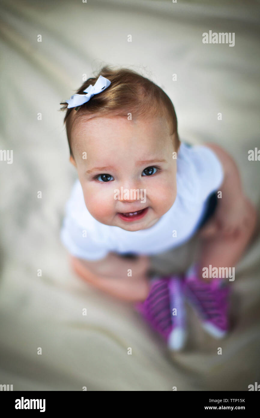 Vue de dessus de toddler sitting on bed sheet Banque D'Images
