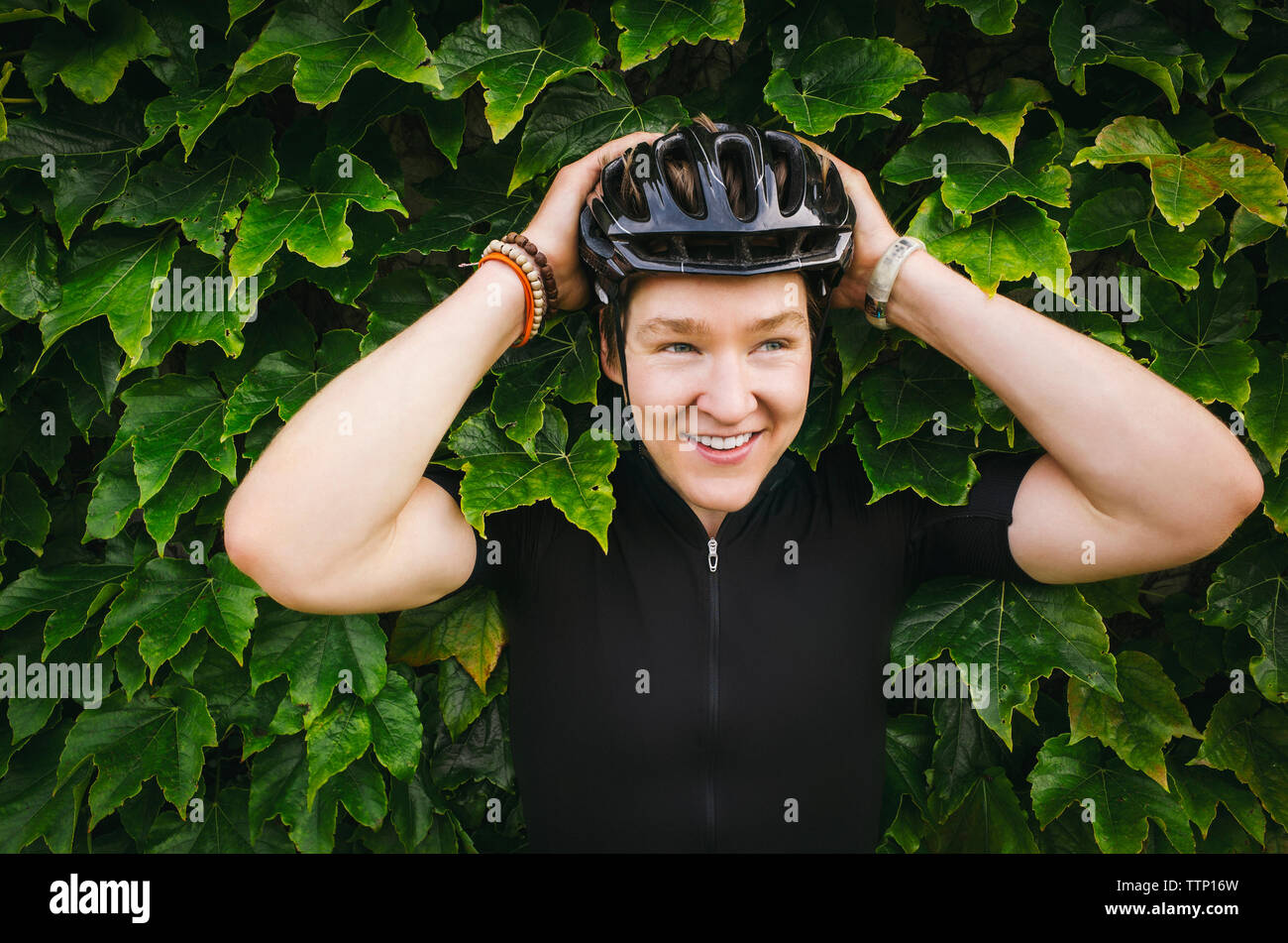Male cyclist wearing helmet contre Ivy Banque D'Images