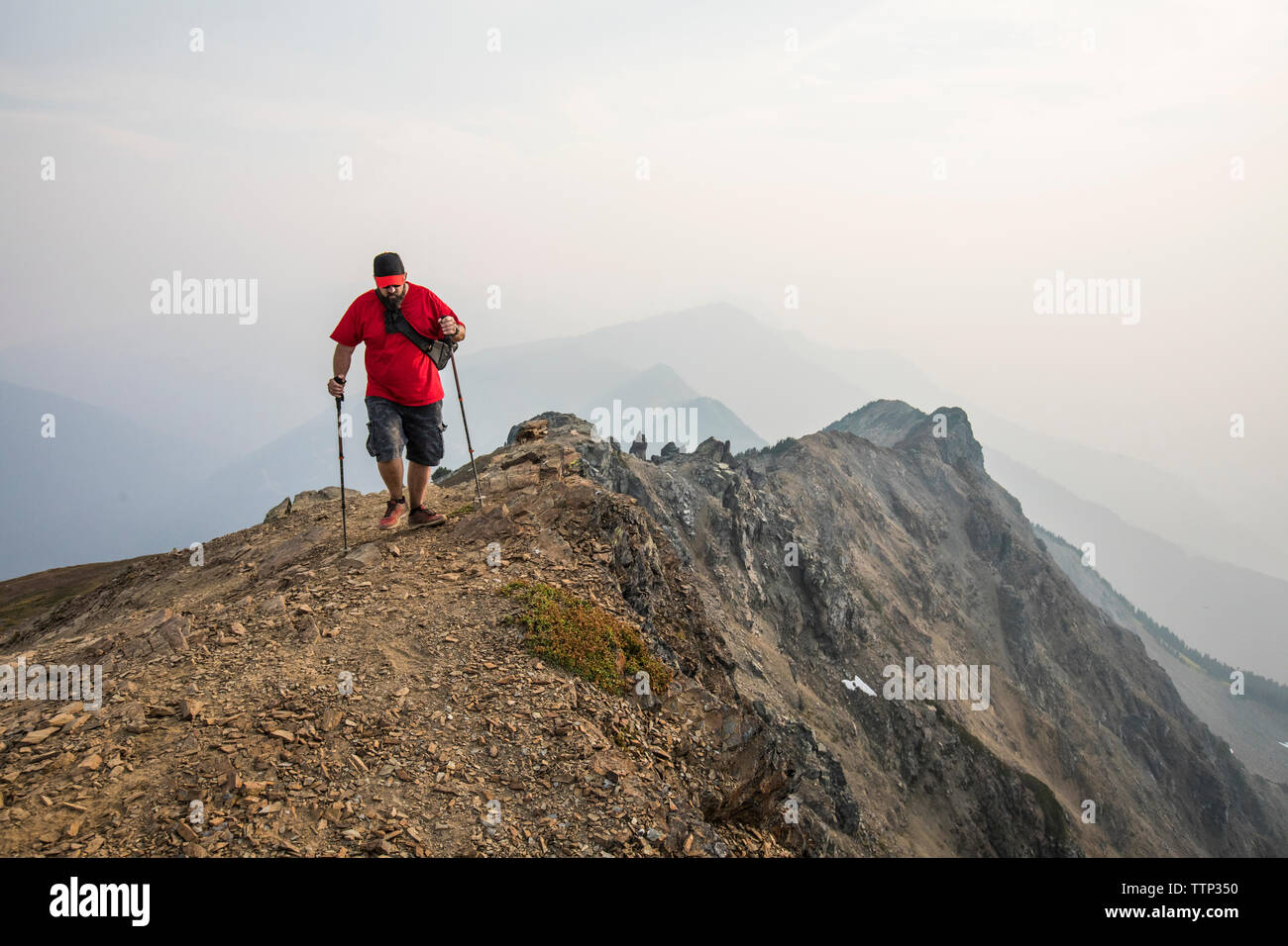 Toute la longueur de l'aide de pôles de randonnée randonneur en marchant sur mountain against sky Banque D'Images