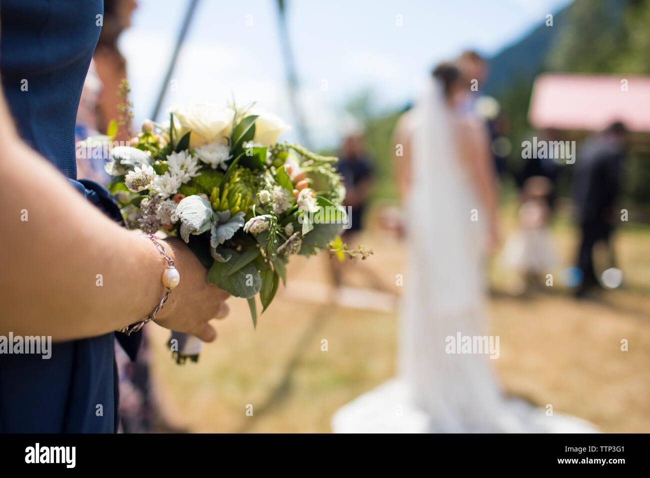 Au milieu du bouquet de demoiselle d'exploitation tout en se tenant à l'encontre de la cérémonie de mariage en couple Banque D'Images