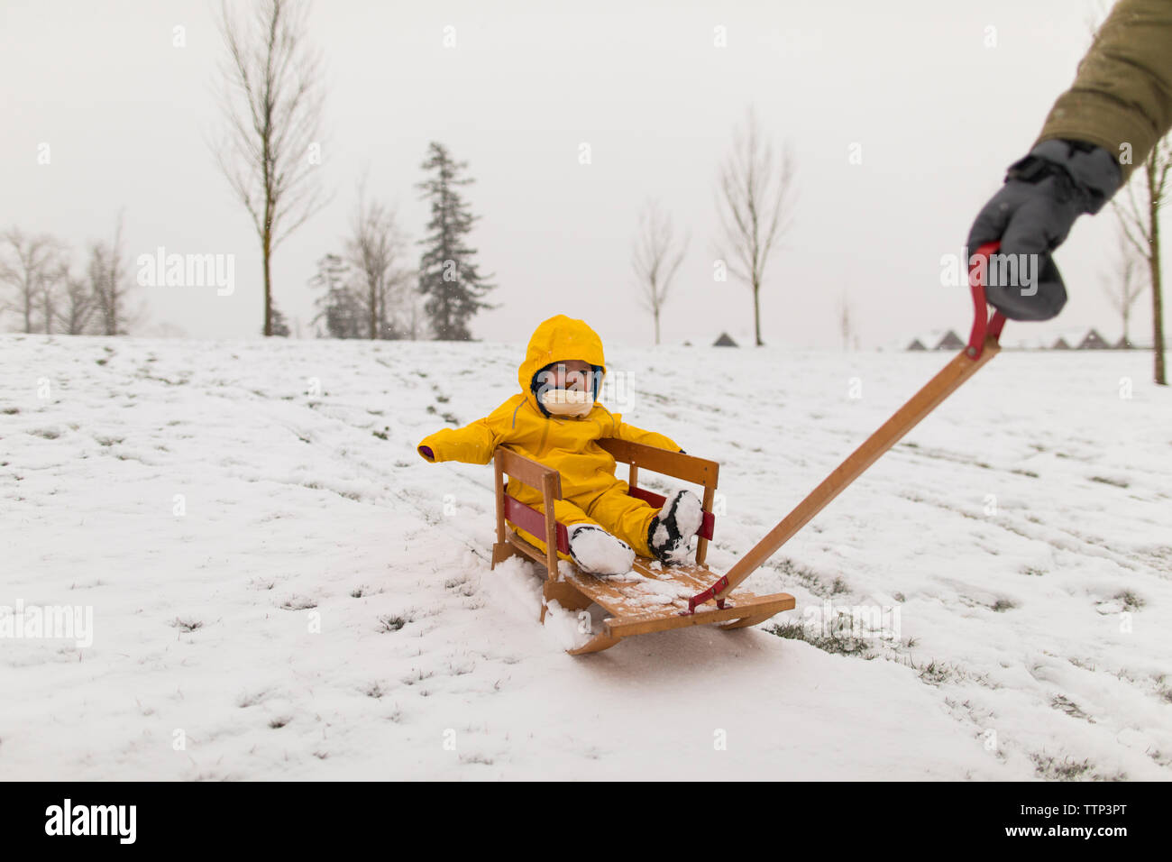 Mère fille bébé tire sur le traîneau en bois après des chutes de neige. Banque D'Images