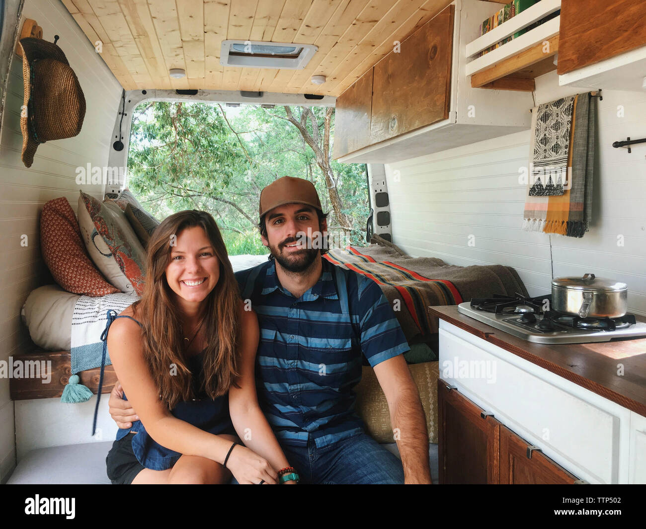 Portrait of happy couple sitting in motor home à forest Banque D'Images