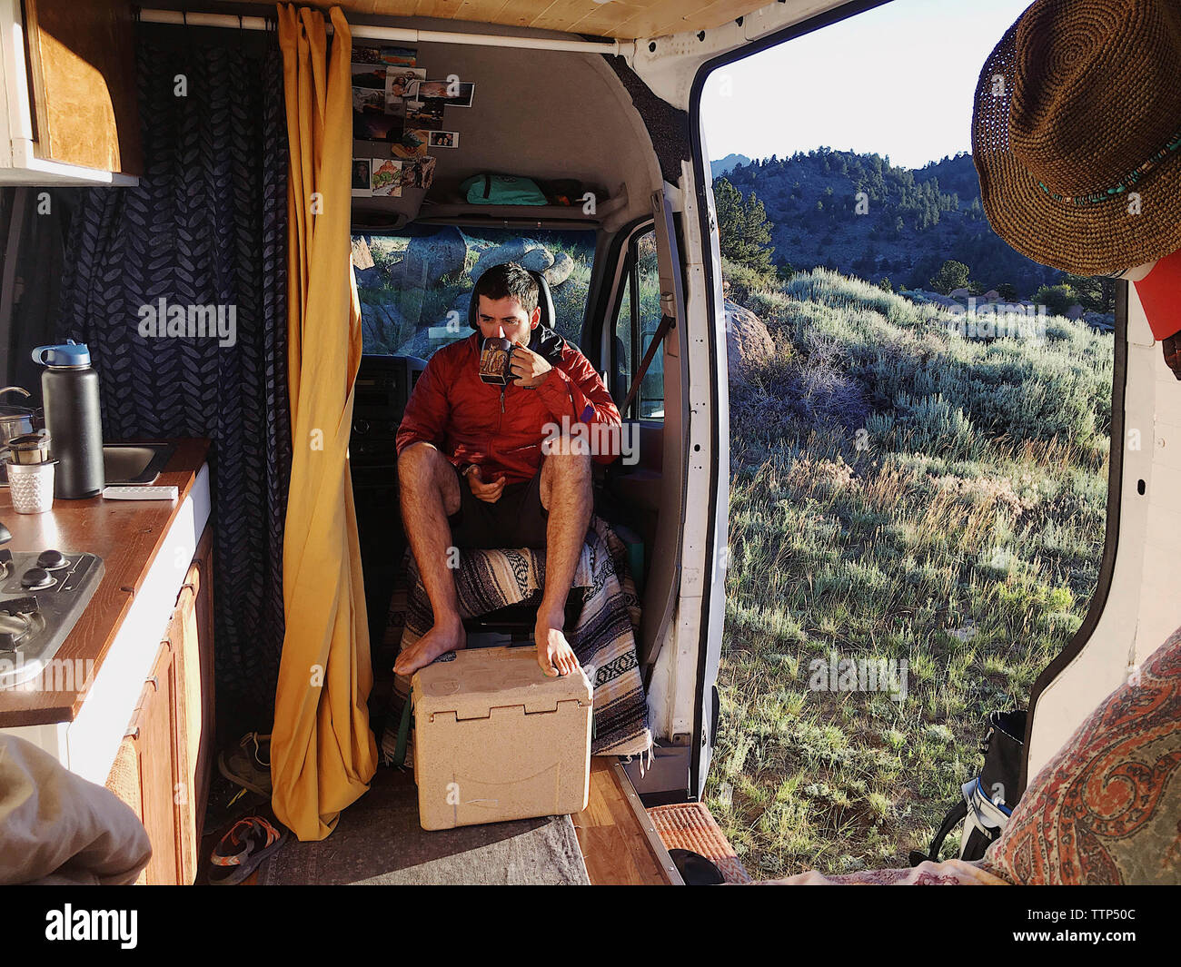 L'homme ayant un verre tout en restant assis dans motor home à forest Banque D'Images