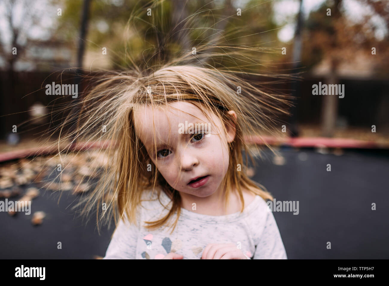 Portrait de fille mignonne avec des cheveux en bataille contre le trampoline à park au cours de l'automne Banque D'Images