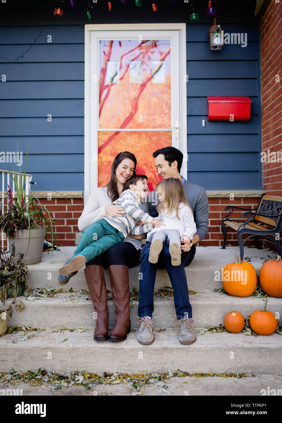 Happy Family sitting on steps against house à l'Halloween Banque D'Images
