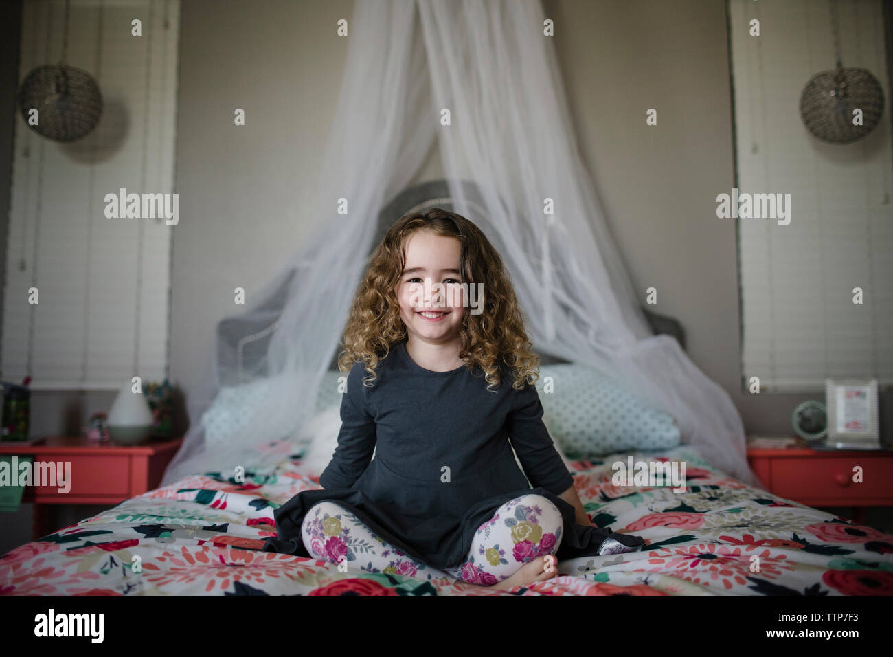 Portrait of cheerful girl sitting on bed at home Banque D'Images