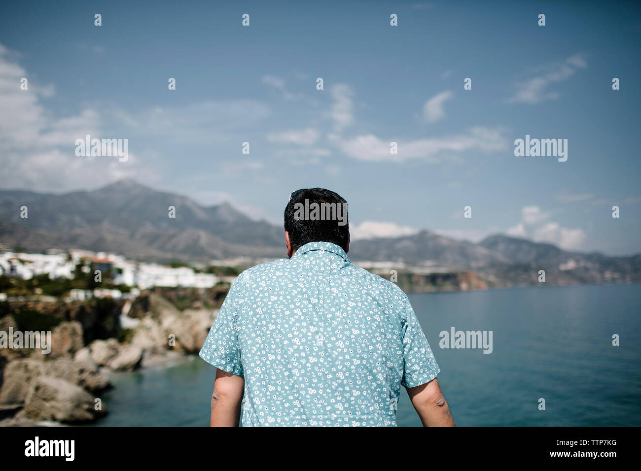 Man looking at view par mer contre montagne et ciel Banque D'Images